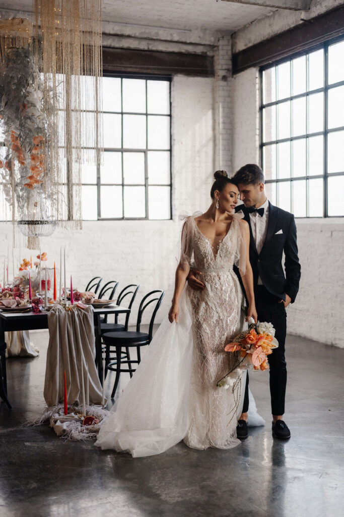 Brautpaar läuft durch eine helle Loft Location an der Hochzeitstafel vorbei, Fotografin Wil