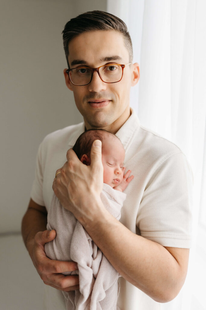 Papa hält sein Neugeborenes im Arm im hellen Studio, Fotografin St. Gallen